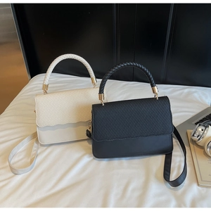 Chic beige and black textured crossbody bags with woven handles on a white surface