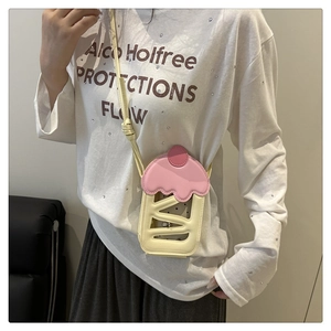 Detail view of the cherry cake inspired crossbody phone bag worn by a model in beige