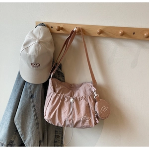 Detail der rosa Nylon-Faltentasche mit verstellbarem Gurt und kleinem runden Anhänger