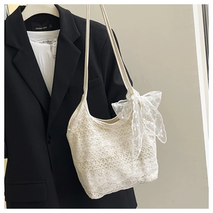 Detail der weißen Spitzen-Tasche mit floralem Häkelmuster und großer seitlicher Schleife