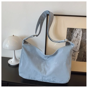 Detail of light blue hobo bag with adjustable strap on a minimalist white countertop