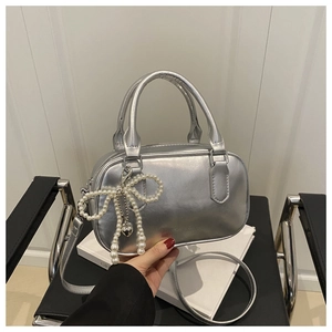 Détail du sac à main argenté métallisé avec pendentif nœud en perles et bandoulière