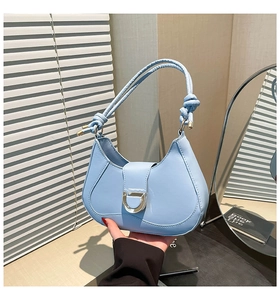 Detail of light blue crescent bag featuring knotted handle and silver metal D-ring closure