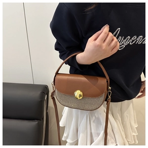 Detail of vintage saddle bag with brown leather, woven texture, and gold metal lock