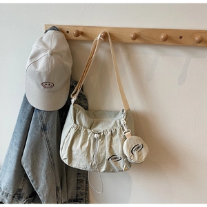 Detail einer beigen Tragetasche mit Kordelzug und kleinem runden Beutel an einem Haken