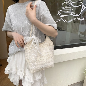 Elegant off-white lace shoulder bag with floral patterns and a large bow charm