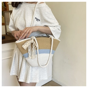 Detail of tricolor woven tote bag featuring beige lace bow and sturdy rope handles
