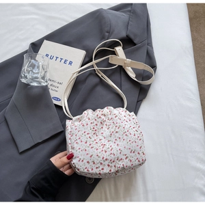 Close-up of floral drawstring bucket bag on grey blazer with minimalist lifestyle props