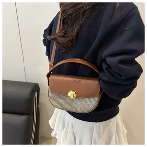 Detail of a half-moon saddle bag featuring brown leather, silver sequins and gold buckle