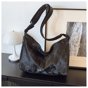 Detail of black nylon tote bag with vintage texture and adjustable strap on a black cabinet