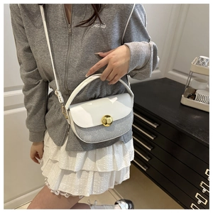 Detail of white leather and silver sequin saddle bag with golden metal buckle and strap
