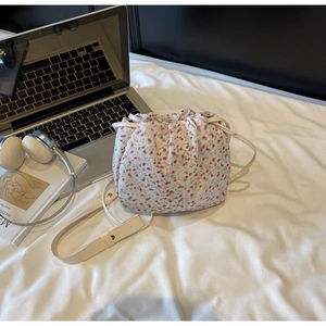 Detail of floral canvas bucket bag with drawstring closure on a desk with laptop and headphones