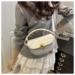 Detail of white leather saddle bag with silver sequins and golden metal buckle