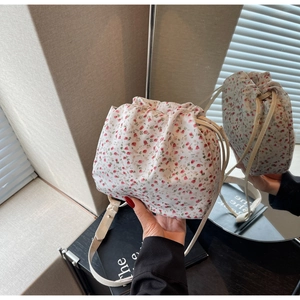 Detailed mirror reflection of floral canvas bucket bag with drawstring and leather strap