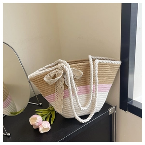 Detail view of woven tote with color blocks, lace bow, and thick rope handle design