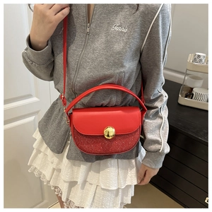 Detail view of red sequin crescent handbag with large gold circular buckle closure