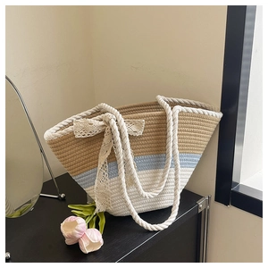 Detail of three-color woven bucket bag featuring a lace bow and nautical rope handles