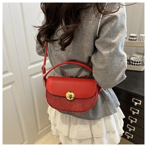 Detail view of red patchwork saddle bag with gold circular buckle on a female model