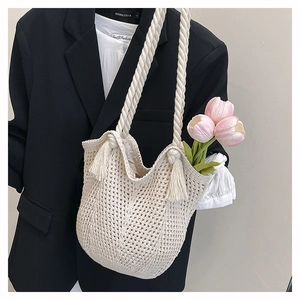 Close-up of beige crochet woven tote bag featuring hollow texture and tassel details