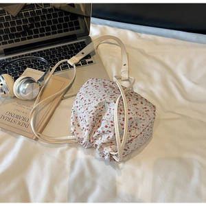 Detail of floral canvas bucket bag with drawstring closure on a cozy bed setting