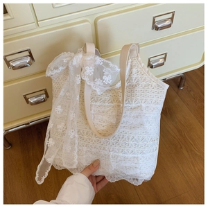 Detail of white lace tote bag featuring multi-layer ruffles and a large bow decoration