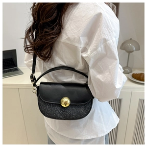 Detail of a chic black half-moon crossbody bag with sequins and gold metal buckle