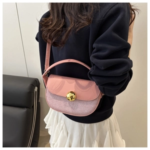 Pink sequin saddle bag with golden spherical clasp shown on model for size and style