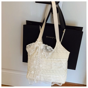 Detailansicht der cremefarbenen Spitzen-Beuteltasche mit Blumenmustern und Schleifendekor