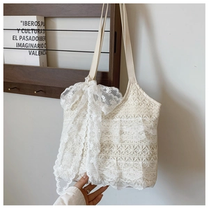 Detailansicht der cremeweißen Häkel-Tasche aus Spitze mit großer Schleife und Blumenmuster