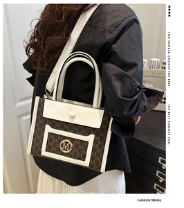 Side view of large tote bag with M-pattern print and white leather patchwork detail