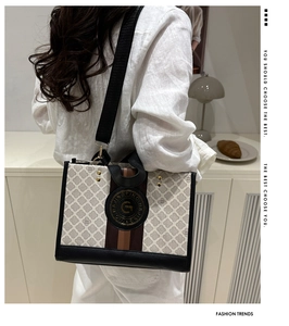 Detail einer gemusterten beige Tote-Tasche mit schwarzen Besatz und Gold-Hardware