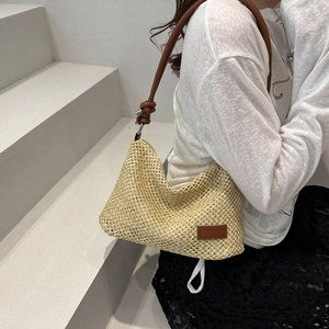 Women's woven straw tote bag with brown leather straps and minimal tassel knot