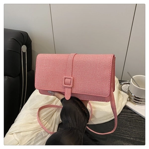 Detail shot of a pink textured baguette bag featuring a woven pattern and square buckle