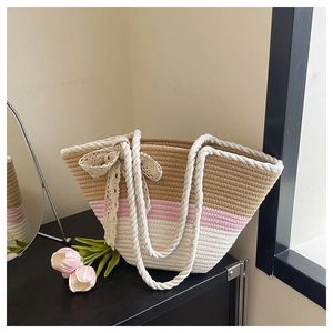 Detail of straw woven tote bag with tricolor patchwork, lace bow, and rope handles