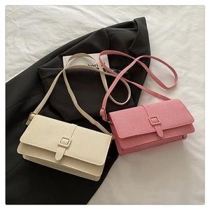 Close-up of beige and pink textured fabric bags with square buckles on blazer background
