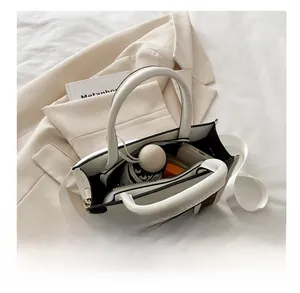Detail view of spacious beige tote bag interior holding phone, umbrella, and wallet