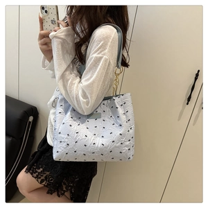 Détail du sac cabas matelassé bleu clair avec motifs nœuds et bandoulière chaîne
