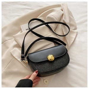 Close-up of black sequins and leather saddle bag with gold round buckle and long strap