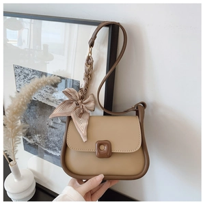 Detail of color-block saddle bag featuring a decorative silk scarf on the handle
