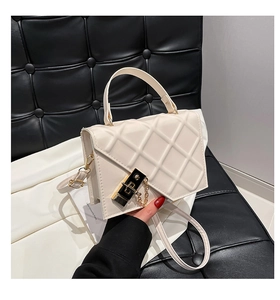 Detailed view of the diamond-quilted texture and gold buckle on the cream shoulder bag