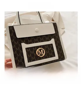 Detail shot of the brown monogram print tote with white leather trim and gold metal logo