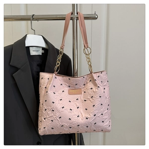 Détail du sac cabas rose matelassé avec nœuds noirs et bandoulière en chaîne