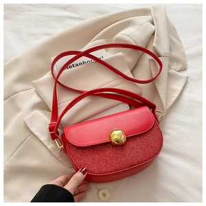 Detail of red saddle bag featuring shimmering sequins and a gold metal buckle closure