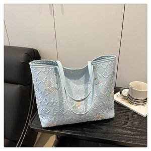 Détail du cabas matelassé bleu clair avec broderie papillon en paillettes colorées