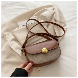 Detail of a brown woven saddle bag with a golden metal buckle on a neutral blazer