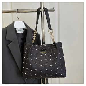 Détail du cabas noir aux motifs de nœuds blancs avec chaîne dorée et lanière en cuir