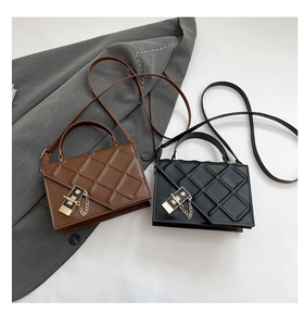 Detailed view of quilted square bags in black and brown with golden metal chain locks