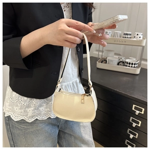 Close-up of textured cream leather shoulder bag with gold zipper held by a model