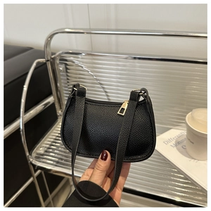 Detail of black pebbled leather texture and gold metal zipper on small shoulder bag
