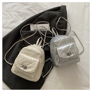 Detail of mini quilted backpacks in cream and silver with metallic chain and turn-lock closure